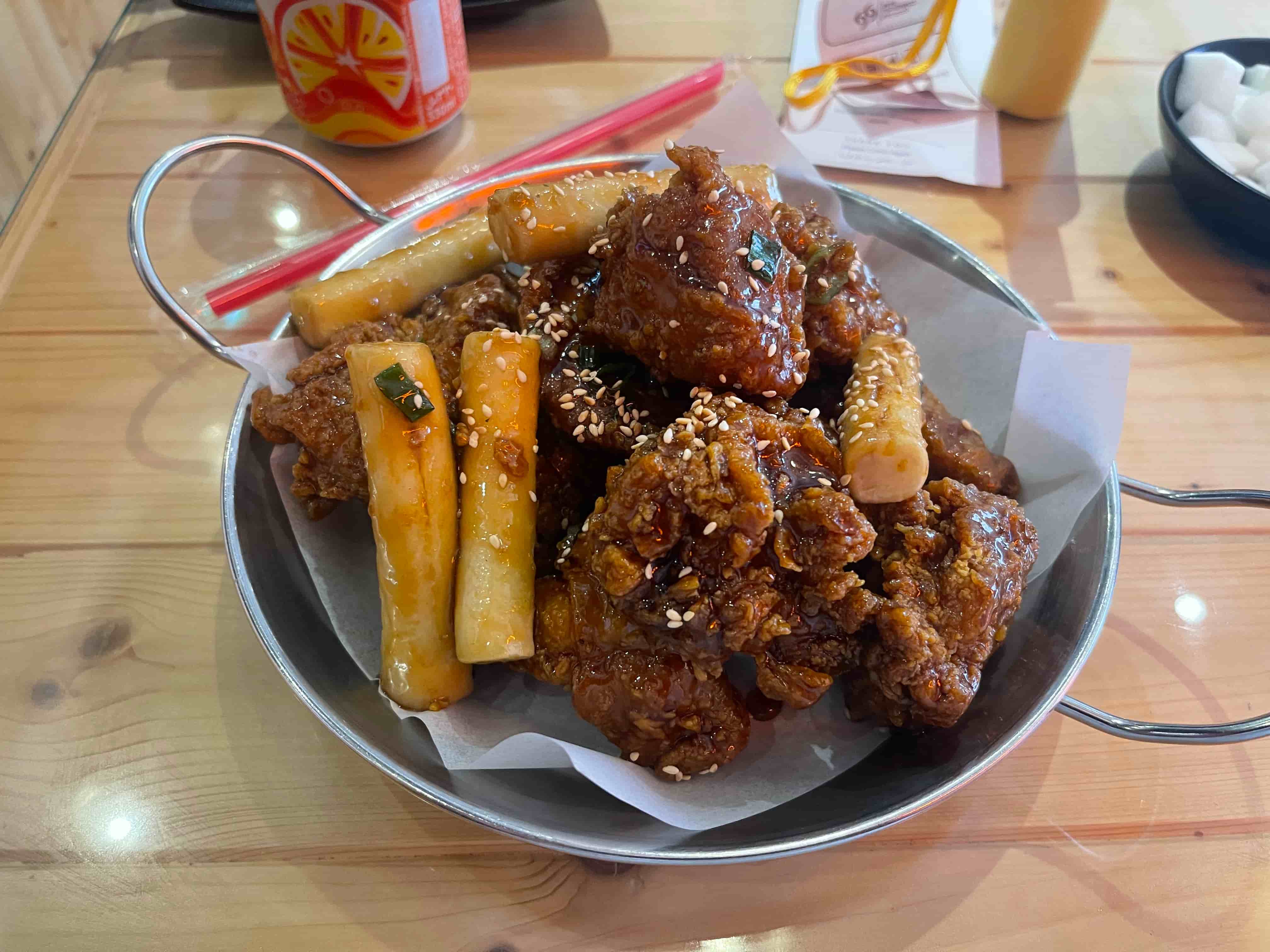 A brown of soy brown fried chicken topped with sesame seeds along with some brown tinged tubulars